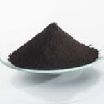 Black iron oxide powder on a clear glass dish for industrial use.