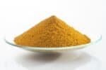 Yellow iron oxide pigment powder on a clear glass dish.