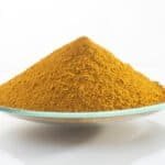 Yellow iron oxide pigment powder on a clear glass dish.