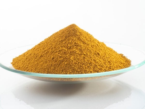 Yellow iron oxide pigment powder on a clear glass dish.
