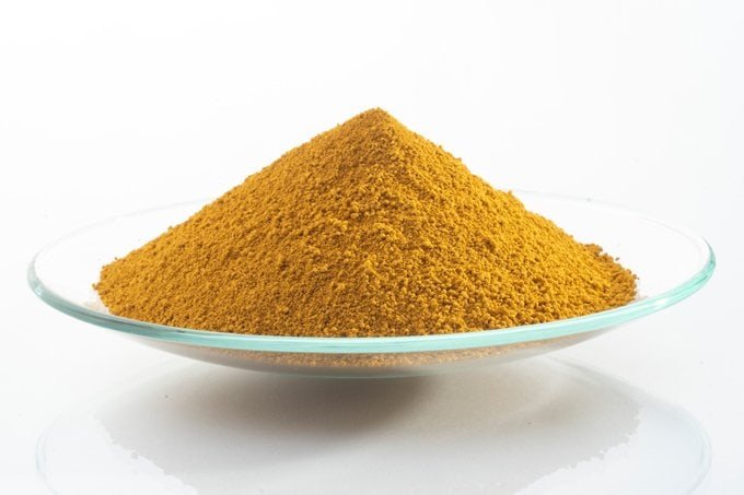 Yellow iron oxide pigment powder on a clear glass dish.